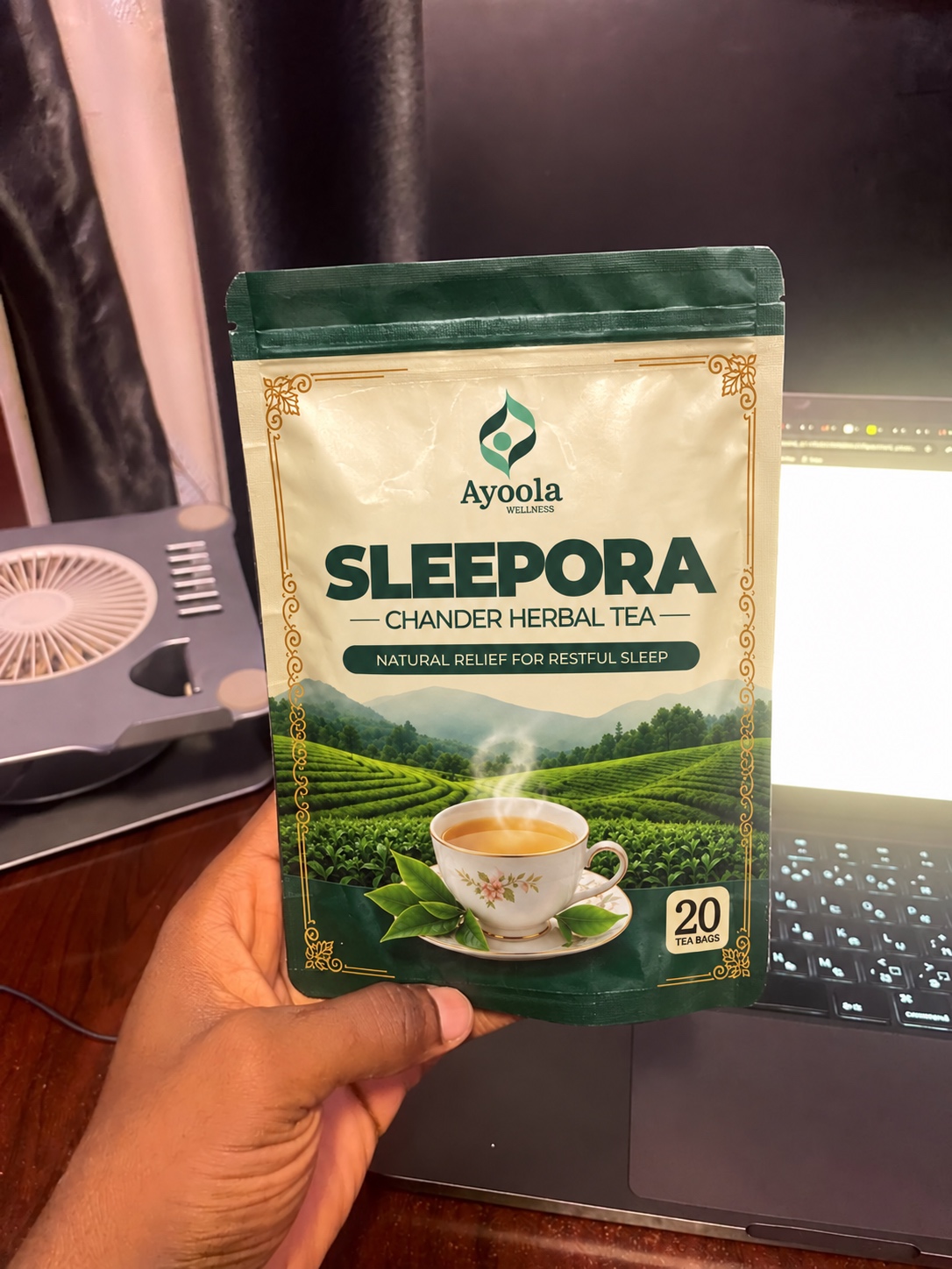 Ayoola SLEEPORA herbal tea pouch held beside a laptop
